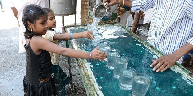 This photo taken on March 18, 2015 shows girls getting a glass of water at a free drinking water distribution stand in Hydera