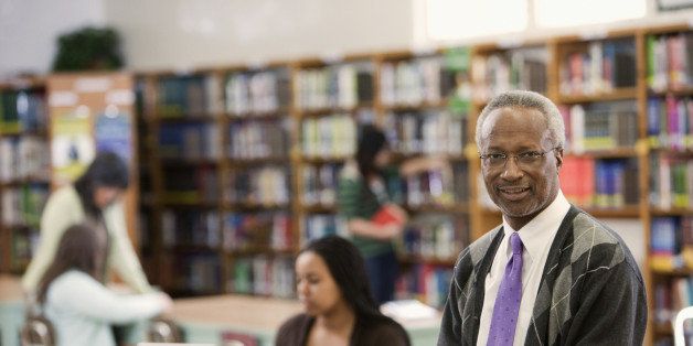 Black librarian reading book in school library