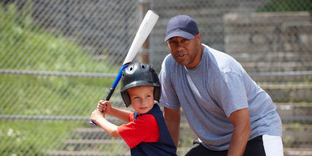 Little League Coach Helping Boy With Batting