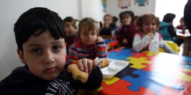 Children eat cakes in a Syrian private school in Mersin, southern Turkey on March 11, 2015 where at least 200.000 Syrians liv