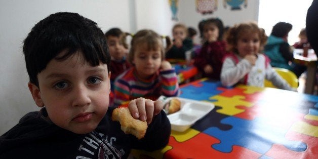 Children eat cakes in a Syrian private school in Mersin, southern Turkey on March 11, 2015 where at least 200.000 Syrians live after feeing the war in their country. Since the Syrian civil war erupted four years ago, tens of thousands of refugees have poured into the southern Turkish port town of Mersin, fearing they may never return home and yearning for a better life. AFP PHOTO/ADEM ALTAN (Photo credit should read ADEM ALTAN/AFP/Getty Images)