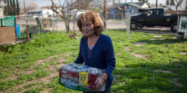 EAST PORTERVILLE, CA - FEBRUARY 11: Evangeline Chavez receives drinking water from Donna Johnson who distributes drinking water to neighbors as water wells supplying hundreds of residents remain dry in the fourth year of worsening drought on February 11, 2015 in East Porterville, California. Many local residents fill water tanks with free non-potable water for flushing toilets, bathing and laundering. Bottled water is used for drinking, cooking and washing dishes. Most of the wells of about 926 dry homes in Tulare County stopped flowing last summer when some 17 California communities ran out of water. (Photo by David McNew/Getty Images)