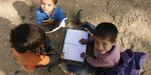 Boys play with a school book at a UNHCR's camp for Syrian refugees in south Lebanon on April 14, 2015. More than 12 million c