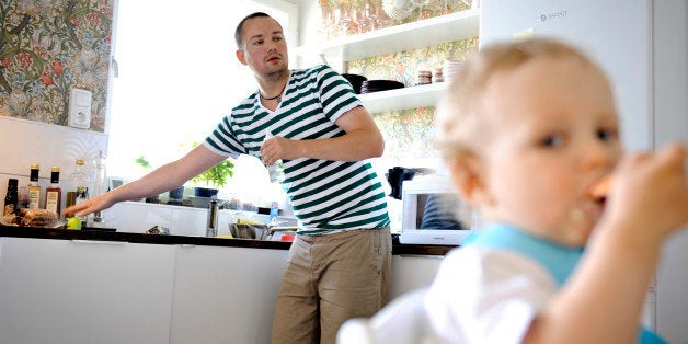 In this Wednesday, June 29, 2011 photo, Henrik Holgersson cares for his son, Arvid, in the kitchen of their home in Stockholm. Holgersson has split Sweden's generous parental leave with his girlfriend Jenny Karlsson and is spending eight months at home with their child. Holgersson, who normally works as a rigger at an event company, says his time with his son as a stay-at-home dad is one of the best in his life. (AP Photo/Niklas Larsson)