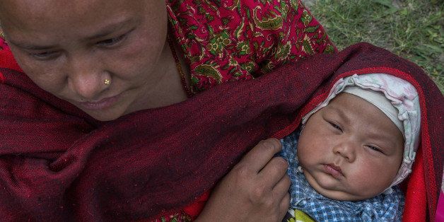 KATHMANDU, NEPAL - APRIL 27: A mother holds her child in an evacuation area set up by the authorities in Tundhikel park on April 27, 2015 in Kathmandu, Nepal. A major 7.8 earthquake hit Kathmandu mid-day on Saturday, and was followed by multiple aftershocks that triggered avalanches on Mt. Everest that buried mountain climbers in their base camps. Many houses, buildings and temples in the capital were destroyed during the earthquake, leaving over 3000 dead and many more trapped under the debris as emergency rescue workers attempt to clear debris and find survivors. (Photo by Omar Havana/Getty Images)