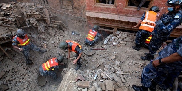 Nepalese Military Police officials search through rubble in the earthquake damaged area of Bhaktapur on the outskirts of Kathmandu on April 28, 2015. Hungry and desperate villagers rushed towards relief helicopters in remote areas of Nepal, begging to be airlifted to safety, four days after a monster earthquake killed nearly 4,500 people. AFP PHOTO/MENAHEM KAHANA (Photo credit should read MENAHEM KAHANA/AFP/Getty Images)