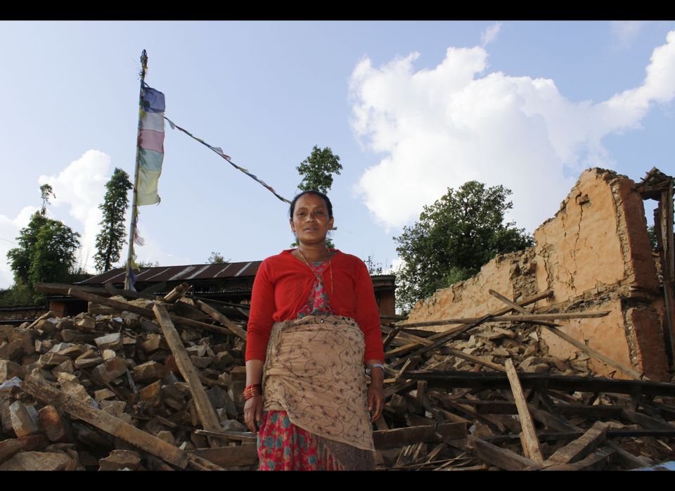 Heifer International Nepal participant stands outside her collapsed home.