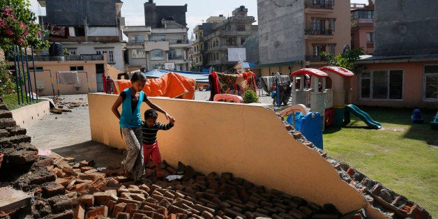 A young girl walks with a boy over a collapsed school playground in Kathmandu, Nepal, Monday, April 27, 2015. A strong magnitude 7.8 earthquake shook Nepal's capital and the densely populated Kathmandu Valley on Saturday, causing extensive damage with toppled walls and collapsed buildings. (AP Photo/Wally Santana)