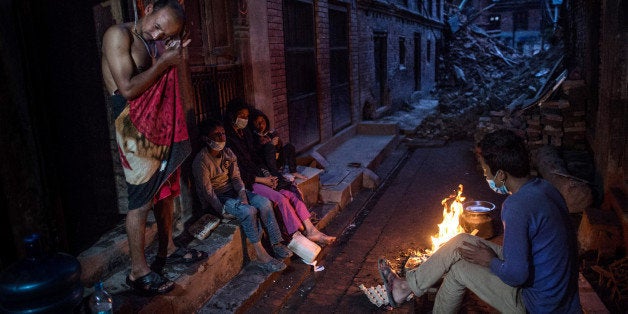 BHAKTAPUR, NEPAL - MAY 03: Members of the Tsayana family warm themselves next to a fire outside their damaged home house on
