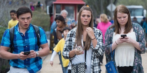 Three teens walk with their smartphones as they walk outside the Natural History Museum in Washington on April 8, 2015. A Pew Research Center survey released found that 92 percent of US teens go online daily. The survey of teens between the ages of 13 and 17 found that 73 percent had a smartphone and 30 percent had at least a basic cellphone. AFP PHOTO/ NICHOLAS KAMM (Photo credit should read NICHOLAS KAMM/AFP/Getty Images)