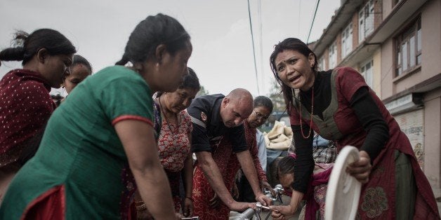 Women get water distributed as relief aid outside Bungamati village in the outskirts of Kathmandu on May 8, 2015. The 7.8 mag