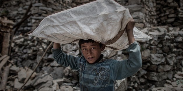 A Nepalese arthquake survivor carries relief supplies delivered by a World Food Programme (WFP) helicopter in the remote Kerauja village in Gorkha district on May 6, 2015. The earthquake that struck Nepal on April 25, 2015, killed more 7,600 people and injured another 16, 390 across the country, according to the Nepal Emergency Operation Centre. AFP PHOTO/Philippe Lopez (Photo credit should read PHILIPPE LOPEZ/AFP/Getty Images)