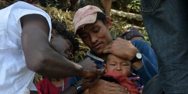 Team members of Medecins Sans Frontieres treat a young earthquake survivor in the village of Ebi in Dhading district some 60k