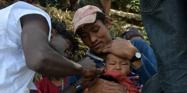 Team members of Medecins Sans Frontieres treat a young earthquake survivor in the village of Ebi in Dhading district some 60kms north-west of Kathmandu on May 11, 2015. The April 25, 2015 disaster completely destroyed 288,798 houses nationwide while 254,112 homes were partially damaged, according to the Himalayan country's National Emergency Operation Center. Large areas of Kathmandu were turned into piles of rubble and almost two weeks on from the 7.8-magnitude quake thousands are still living in makeshift tents in the capital. AFP PHOTO / PRAKASH MATHEMA (Photo credit should read PRAKASH MATHEMA/AFP/Getty Images)