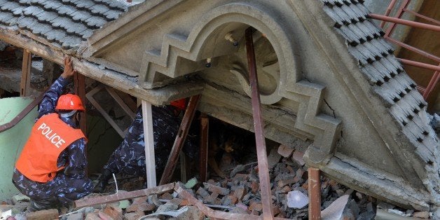 Rescue team officials and a sniffer dog search for survivors at a collapsed house in Kathmandu May 12, 2015, after an earthqu