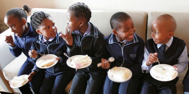 Children at the Bertrams Junior School eat birthday cake as they celebrate their school's 90th anniversary as well as Nelson Mandela's 90th birthday at the Nelson Mandela Foundation in Johannesburg Friday July 18, 2008. Mandela celebrated his 90th birthday Friday by urging the wealthy to share with the less fortunate and by saying he wished he had been able to spend more time with his family during the anti-apartheid struggle. Mandela was imprisoned for nearly three decades for his fight against apartheid.(AP Photo/Denis Farrell)