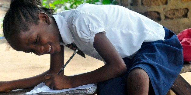 In this photo taken on Friday, May 8, 2015, Mercy Kennedy smiles as she does her home work after school at her home in Monrov
