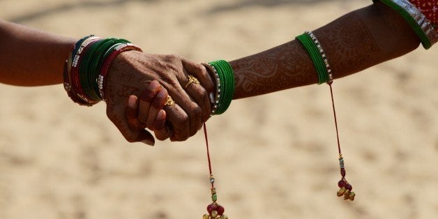 Girls dressed in traditional Rajasthani clothing hold hands as they wait for the start of a traditional dance presentation at