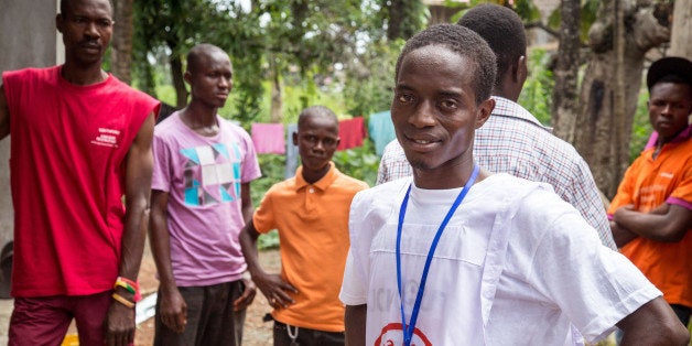 In this photo taken on Friday, Sept. 19, 2014, Idrissa Kargbo, Sierra Leone's national marathon champion, helps volunteers distribute information on Ebola in Freetown, Sierra Leone. As a boy, marathon runner Idrissa Kargbo sprinted through the villages of Sierra Leone on errands for his grandmother and later as a coffee courier. Now at 23 years old, his times have qualified him for races on three continents. (AP Photo/ Michael Duff)