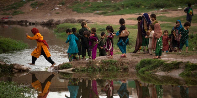 Children who are displaced from Pakistani tribal areas, where security forces are fighting against militants, cross a stream