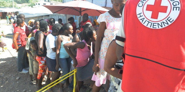 People receive medical kits to aid in the prevention of cholera on February 11, 2011 from the International Red Cross in a city tent in Delmas, a suburb of Port-au-Prince. AFP PHOTO/Thony BELIZAIRE (Photo credit should read THONY BELIZAIRE/AFP/Getty Images)