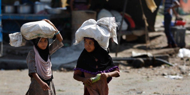 Indian child laborers carry sacks of vegetable leftovers collected from a wholesale market to be sold in their shantytown, on