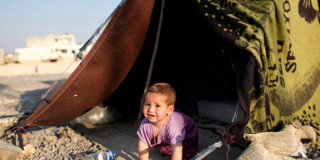 SANLIURFA, TURKEY - JUNE 17: A Syrian refugee child plays in front of their makeshift shelter near a truck close to the Turkish border post of Akcakale, province of Sanliurfa, on June 17, 2015. Some hundreds of Syrian refugees are returning to Tal Abyad from Turkey a day after Kurdish People's Protection Units, or YPG fighters evicted Islamic State group fighters from the area. According to the UNHCR, the Kurdish advance caused the displacement of about 23,000 people who fled into Turkey from the fighting in the past two weeks. (Photo by Gokhan Sahin/Getty Images)