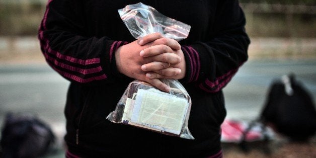 A syrian migrant holds family's documents and passports after disembarking on the island of Lesbos on June 18, 2015. Some 48,000 migrants and refugees have landed on Greek shores so far this year, compared to 34,000 arrivals during all of 2014, according to the International Organization for Migration (IOM). AFP PHOTO / LOUISA GOULIAMAKI (Photo credit should read LOUISA GOULIAMAKI/AFP/Getty Images)