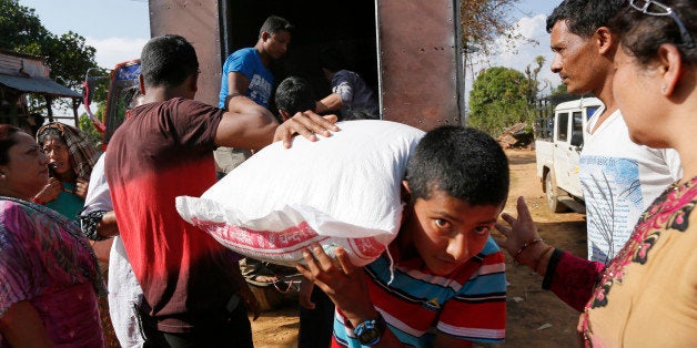 In this photo taken on Saturday, May 2, 2015, villagers, young and old, carry donated aid in the destroyed village of Pokhari