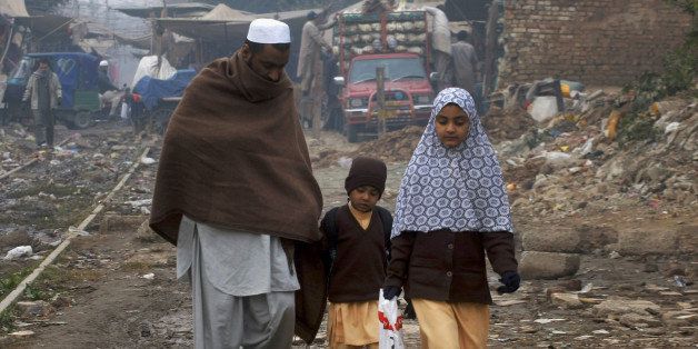 A Pakistani man walks his children home after their school Saturday, Dec. 20, 2014 in Peshawar, Pakistan. The attack of the Taliban, who carried out a school massacre in the city earlier this week, killing 148 people, mainly children, shocked the nation and prompted a massive military response in the tribal regions along the Afghan border, longtime strongholds of both foreign and local militants. (AP Photo/Mohammad Sajjad)
