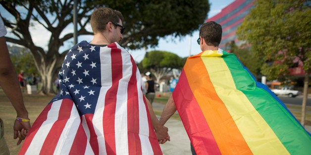 WEST HOLLYWOOD, CA - JUNE 26: Robert Oliver and Mark Heller (R) hold hands, draped in flags, as they celebrate the Supreme C