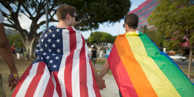 WEST HOLLYWOOD, CA - JUNE 26: Robert Oliver and Mark Heller (R) hold hands, draped in flags, as they celebrate the Supreme Court ruling on same-sex marriage on June 26, 2015 in West Hollywood, California. The Supreme Court ruled today that same-sex couples have a constitutional right to marry nationwide without regard to their state's laws. (Photo by David McNew/Getty Images)