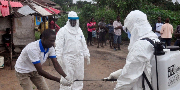 Health workers wash their hands after taking a blood specimen from a child to test for the Ebola virus in an area where a 17-