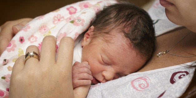 'Newborn premature baby girl, just two days old, resting on her mother's breast.'