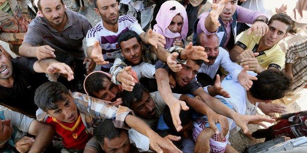 Displaced Iraqis from the Yazidi community gather for humanitarian aid at the Syria-Iraq border at Feeshkhabour border point, northern Iraq, Sunday, Aug. 10, 2014. Kurdish authorities at the border believe some 45,000 Yazidis passed the river crossing in the past week and thousands more are still stranded in the mountains. (AP Photo/ Khalid Mohammed)