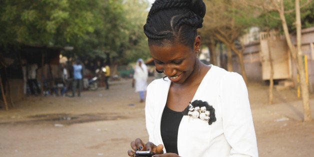 A smiling young woman writing a texto on her mobile phone.