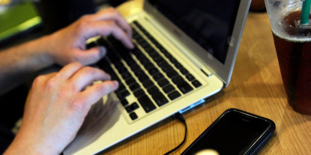 FILE - In this May 13, 2009, file photo, Jonathan Hutcheson works on his laptop as his iPhone lays beside it at a coffee shop in Columbia, Mo. As more tech-savvy young people enter the workforce, they're asking employers to give them more access to social networking and other sites, both for work purposes and when they'd like to take a break from their jobs. (AP Photo/L.G. Patterson, File)