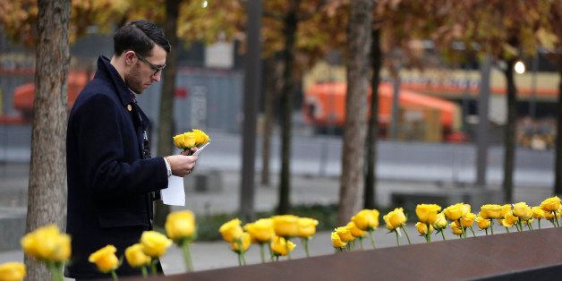 A volunteer for the 9/11 Memorial and Museum places yellow roses into carved names of veterans who were killed at the World Trade Center during the Sept. 11 attacks at the South Pool of the National September 11 Memorial, Tuesday, Nov. 11, 2014, in New York. The placement of the roses was the last of a five-day Salute to Service honoring veterans at the 9/11 Memorial and Museum in recognition of Veterans Day. (AP Photo/Julie Jacobson)