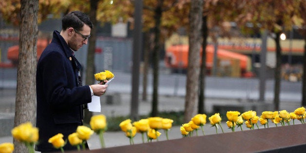 A volunteer for the 9/11 Memorial and Museum places yellow roses into carved names of veterans who were killed at the World T