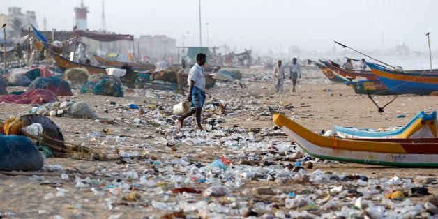 An Indian fisherman walks amidst, plastic and other garbage that got washed ashore on the Bay of Bengal coast in Chennai, India, Thursday, Aug.13, 2015. (AP Photo/Arun Sankar K)