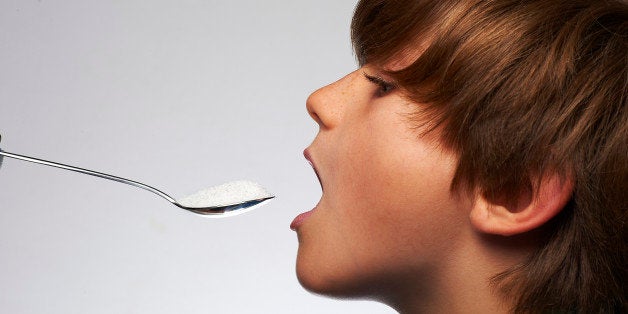 Boy (9yrs) about to eat white sugar from a spoon