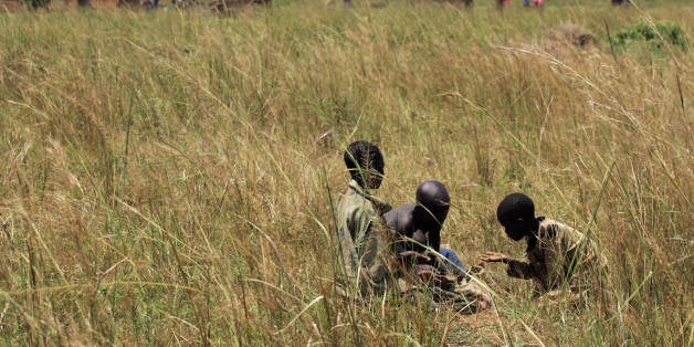 Boys gather kernels of of sorghum that were dispersed on the ground after an air drop in the Olilim camp for Internally displaced people in the Lira District of Northern Uganda, 19 October 2007. The UN food agency said 18 October that food airdrops that started four days earlier have saved up to 250,000 war displaced people from starvation. Alix Loriston, the World Food Programme Deputy Country Director, said in an interview that the operation has so far dropped 143 metric tones of food to IDP camps in Kitgum district after roads linking them to the rest of the country were washed away by floods following torrential rains that have hit the region. AFP PHOTO / Roberto Schmidt (Photo credit should read ROBERTO SCHMIDT/AFP/Getty Images)