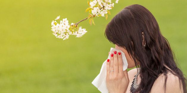 The beautiful young woman is pained by her allergy every year. She holds a tissue in her hands.