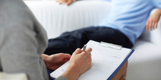 Female psychologist making notes during psychological therapy session