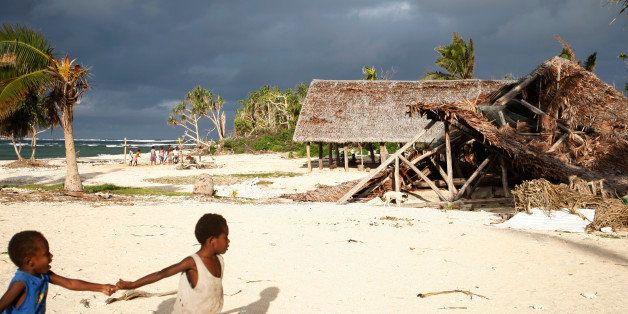 In this Saturday, May 30, 2015, photo, children play on the beach in the town of Takara, on Efate Island, Vanuatu. The town was damaged in March during Cyclone Pam. Many people in the town are considering rebuilding their community on higher ground to escape what they believe are the ongoing effects of climate change. (AP Photo/Nick Perry)