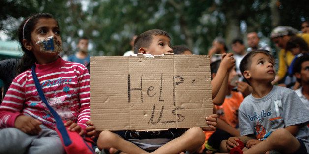 A child holds up a sign as migrants stage a protest in a stadium used for traditional Kirkpinar Oil Wrestling as they wait to walkdown a highway towards Turkeyâs western border with Greece and Bulgaria, in Edirne, Turkey, Monday, Sept. 21, 2015. The migrants were stopped Friday by Turkish law enforcement on a highway near the city of Edirne, causing a massive traffic jam. (AP Photo/Emrah Gurel)