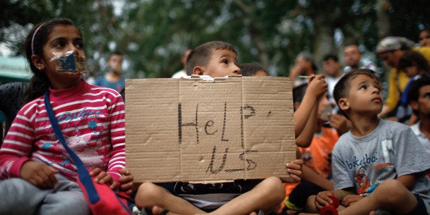 A child holds up a sign as migrants stage a protest in a stadium used for traditional Kirkpinar Oil Wrestling as they wait to