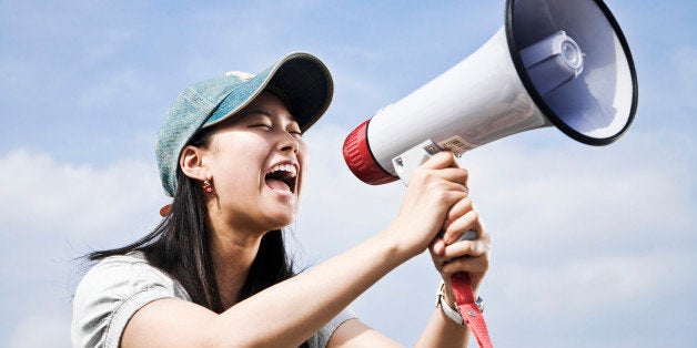 portrait of young japanese woman shouting through megaphone