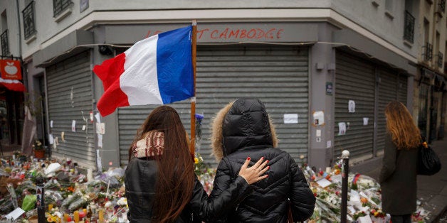 Two women stand outside the Petit Cambodge restaurant, a site of last Friday's attacks, in Paris, Tuesday, Nov. 17, 2015. France made an unprecedented demand on Tuesday for its European Union allies to support its military action against the Islamic State group as it launched new airstrikes on the militants' Syrian stronghold, days after attacks in Paris linked to the group killed at least 129 people. (AP Photo/Daniel Ochoa de Olza)