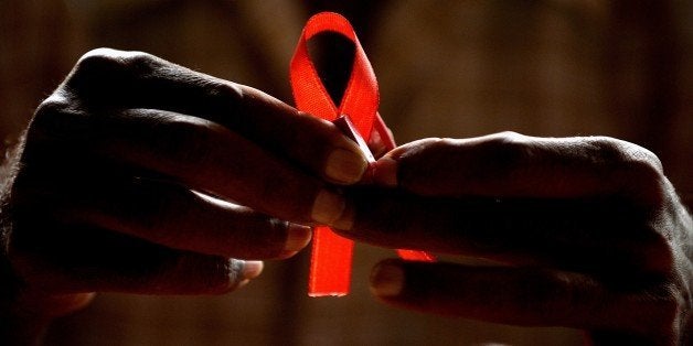 A HIV-positive person from the Support and Care Centre of the Sumanahalli Society prepares 'red ribbons' on the eve of World